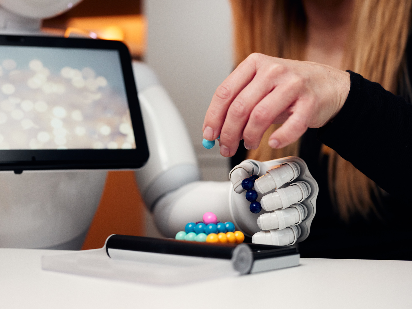 Eine menschliche und eine Roboterhand setzen gemeinsam ein Kugelpuzzle zusammen