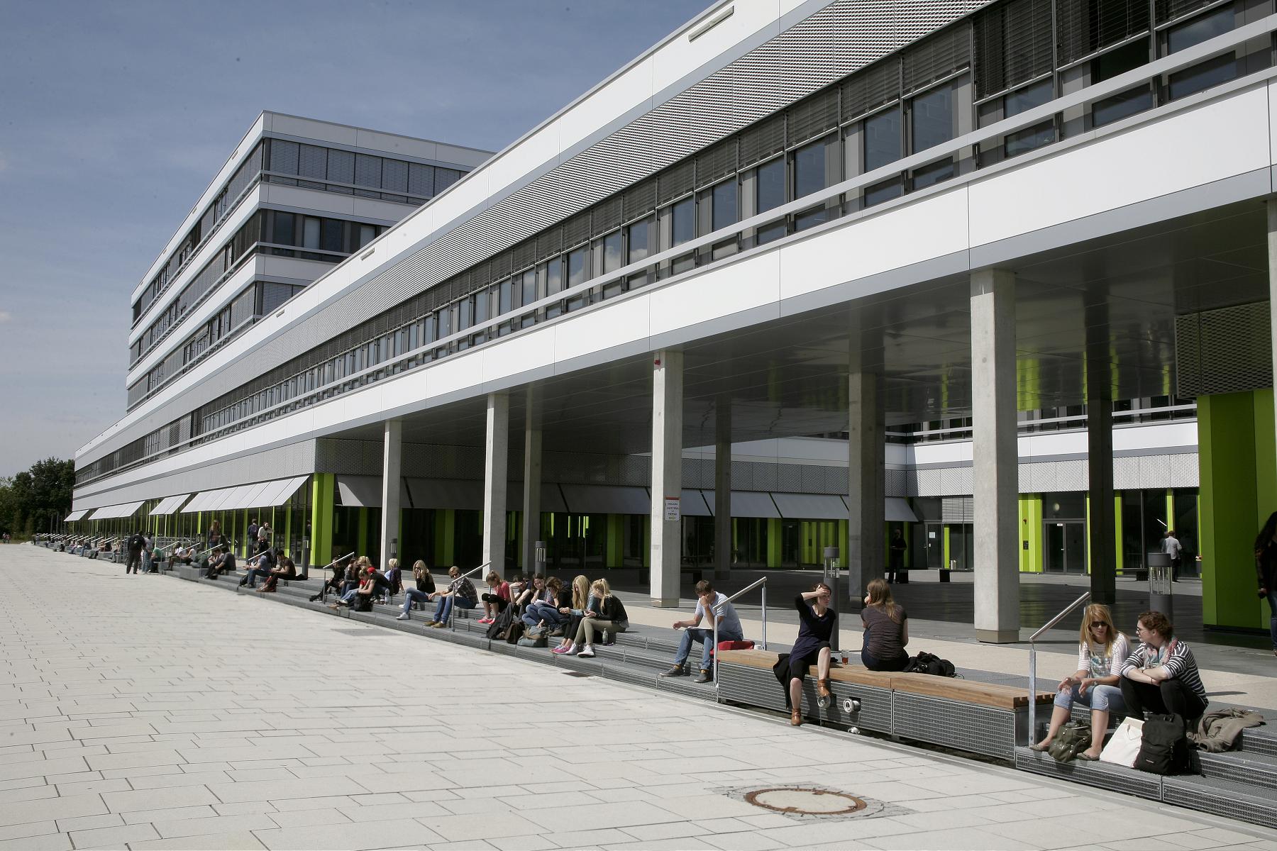Sitzende Studierende vor dem Gebäude X der Universität Bielefeld.