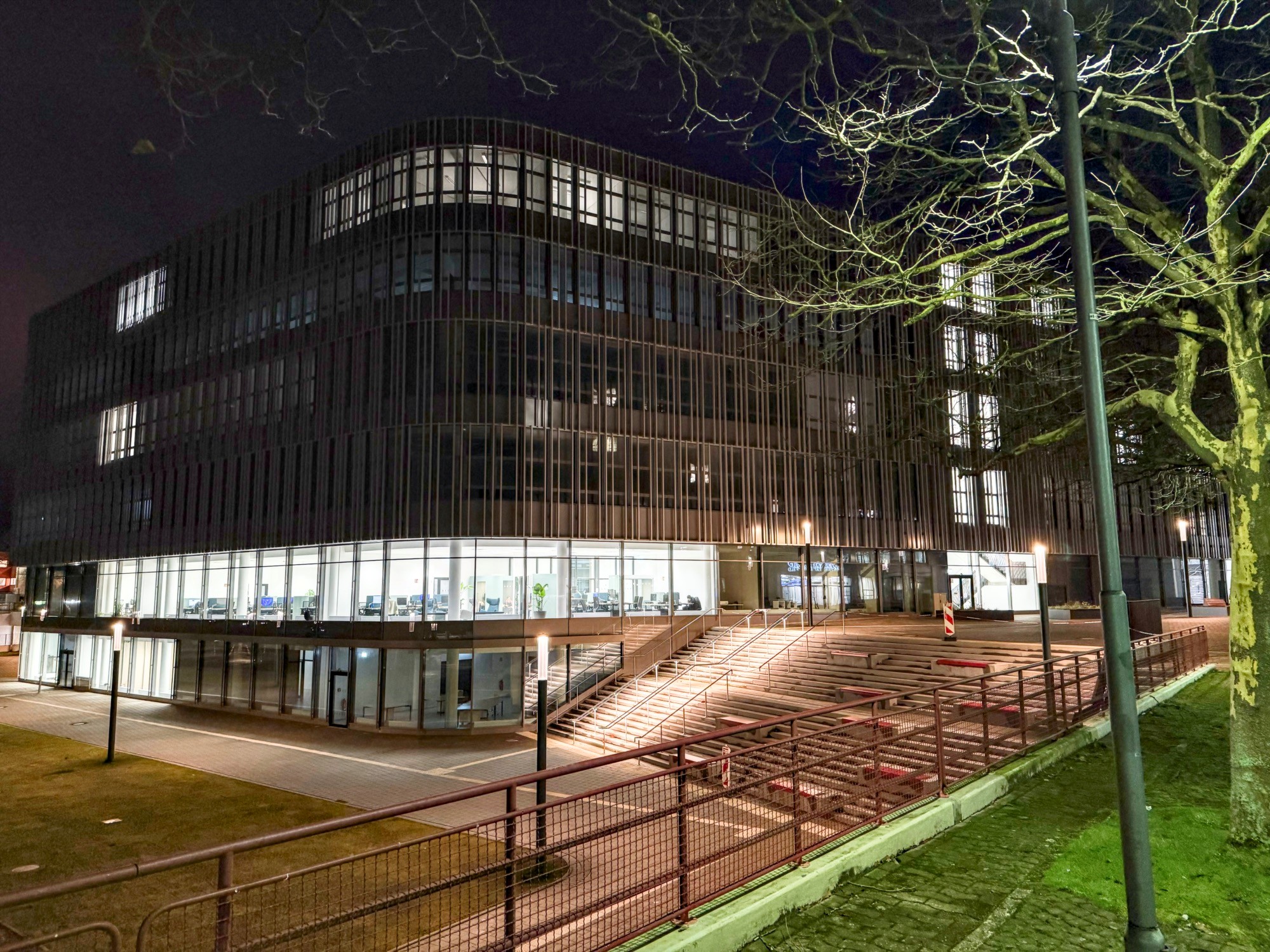 Drei Studierende sitzen vor einem Graffiti in der Halle des Universitätshauptgebäudes.