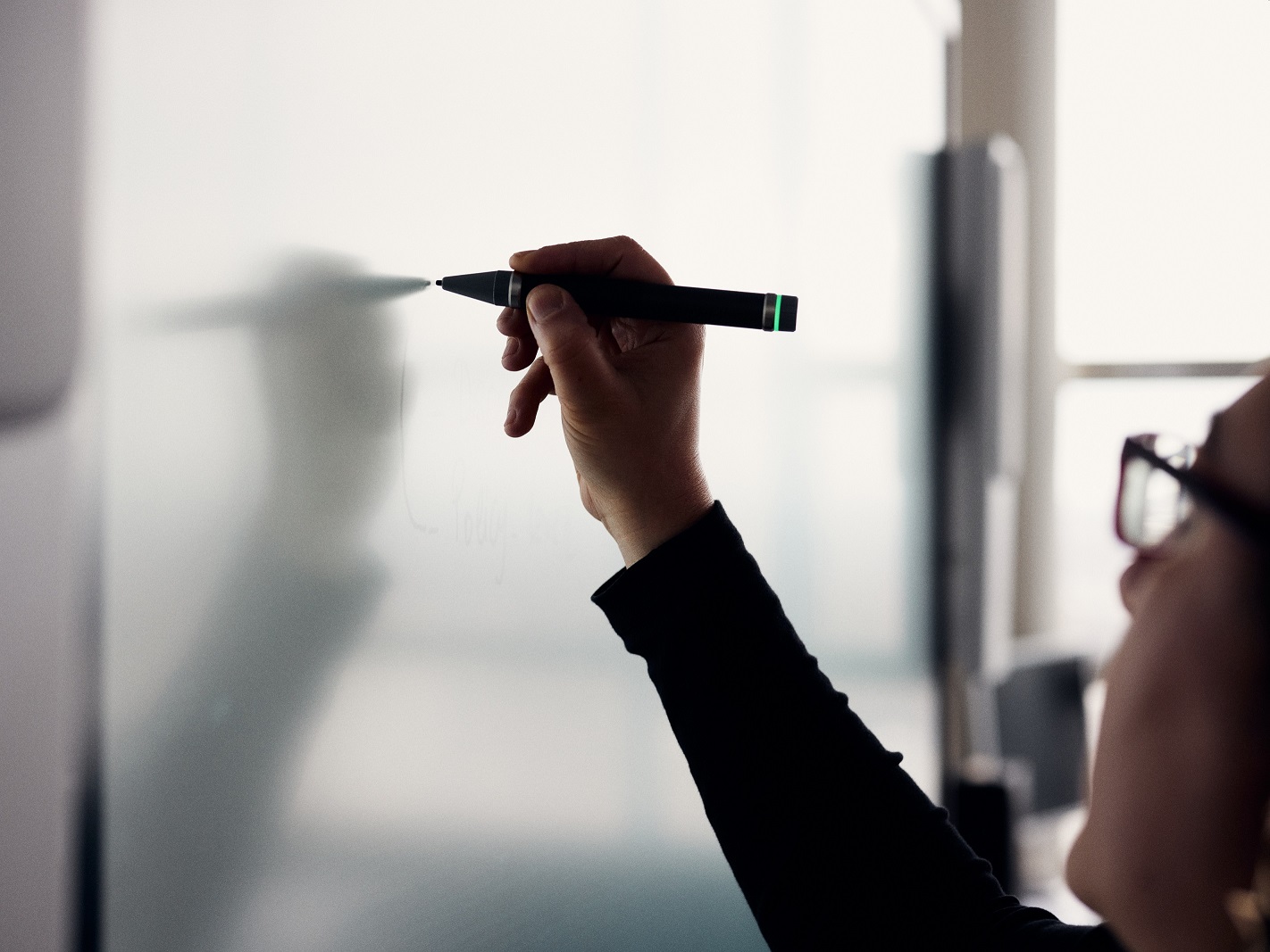 Hand einer Person, die mit einem Stift auf eine weie Tafel schreibt