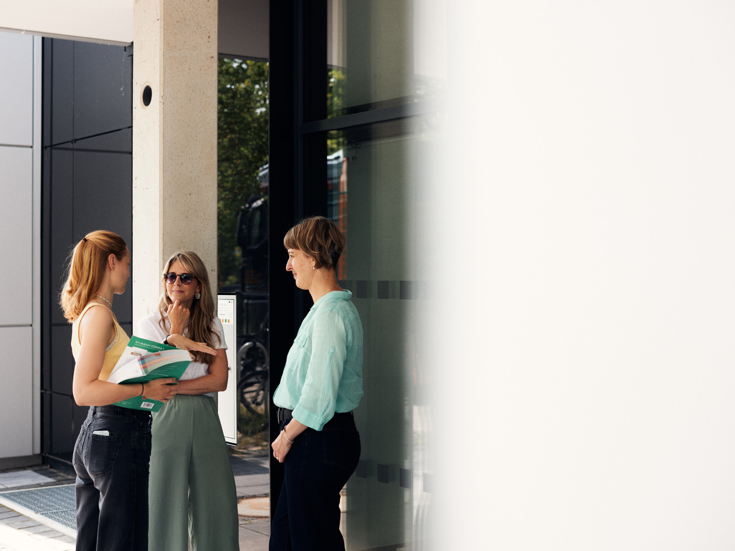 3 Frauen stehen vor einem Gebäude und unterhalten sich