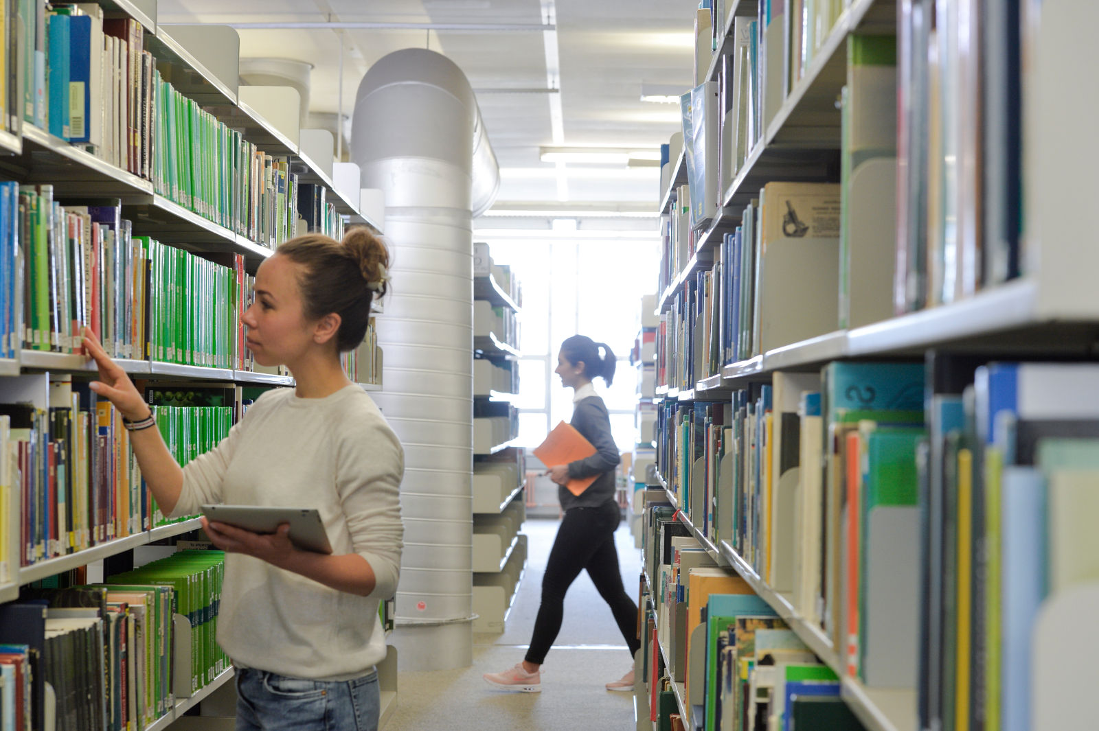 Foto einer Person am Laptop in der Bibliothek