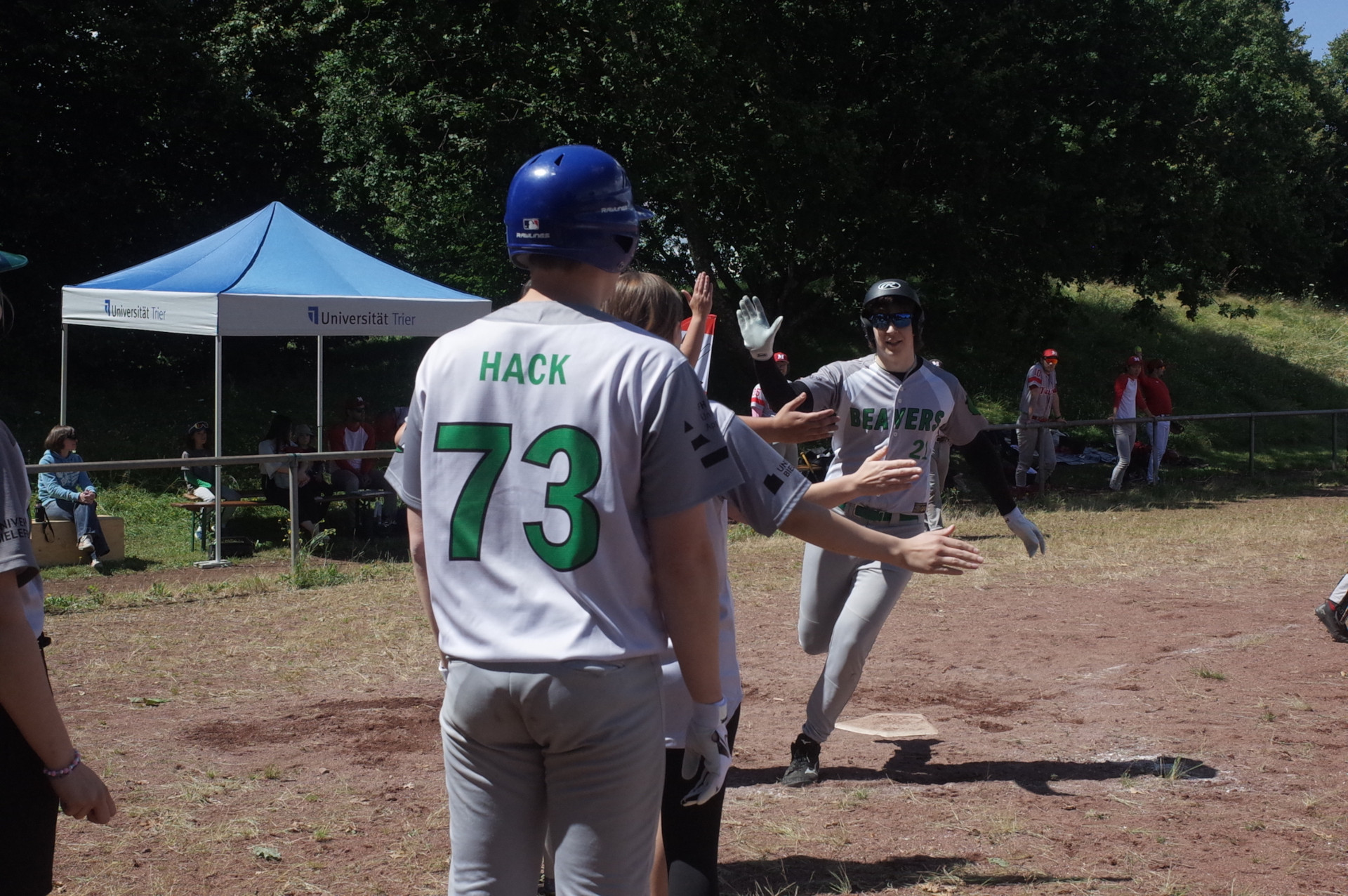 ein Runner der Beavers läuft über die Homeplate; dahinter warten Teamkolleg*innen darauf, ihn abzuklatschen