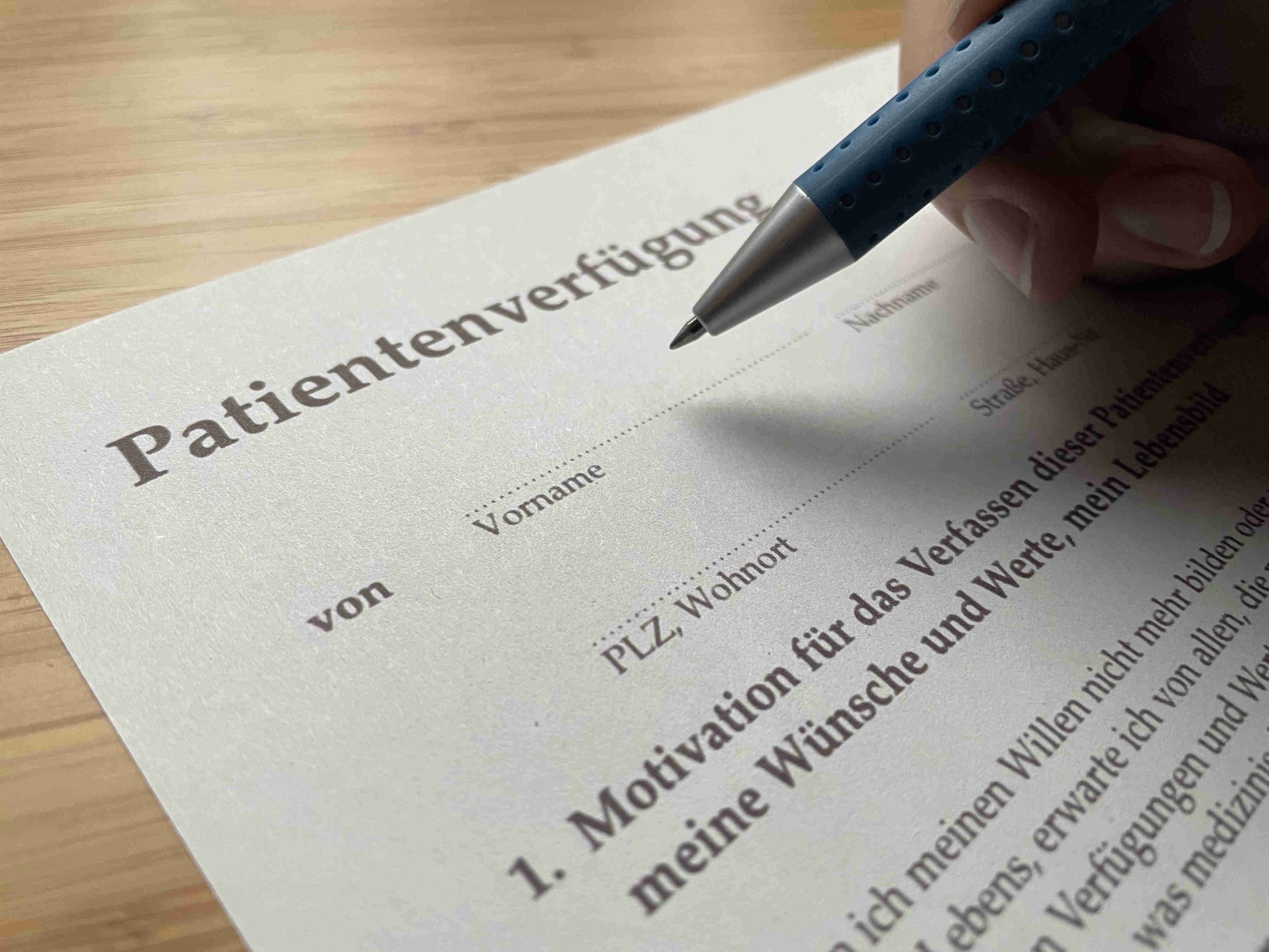 Ein Vordruck für eine Patientenverfügung wird ausgefüllt. Es sind ein Ausschnitt des Formulars und eine Hand, die einen Stift hält, zu sehen.