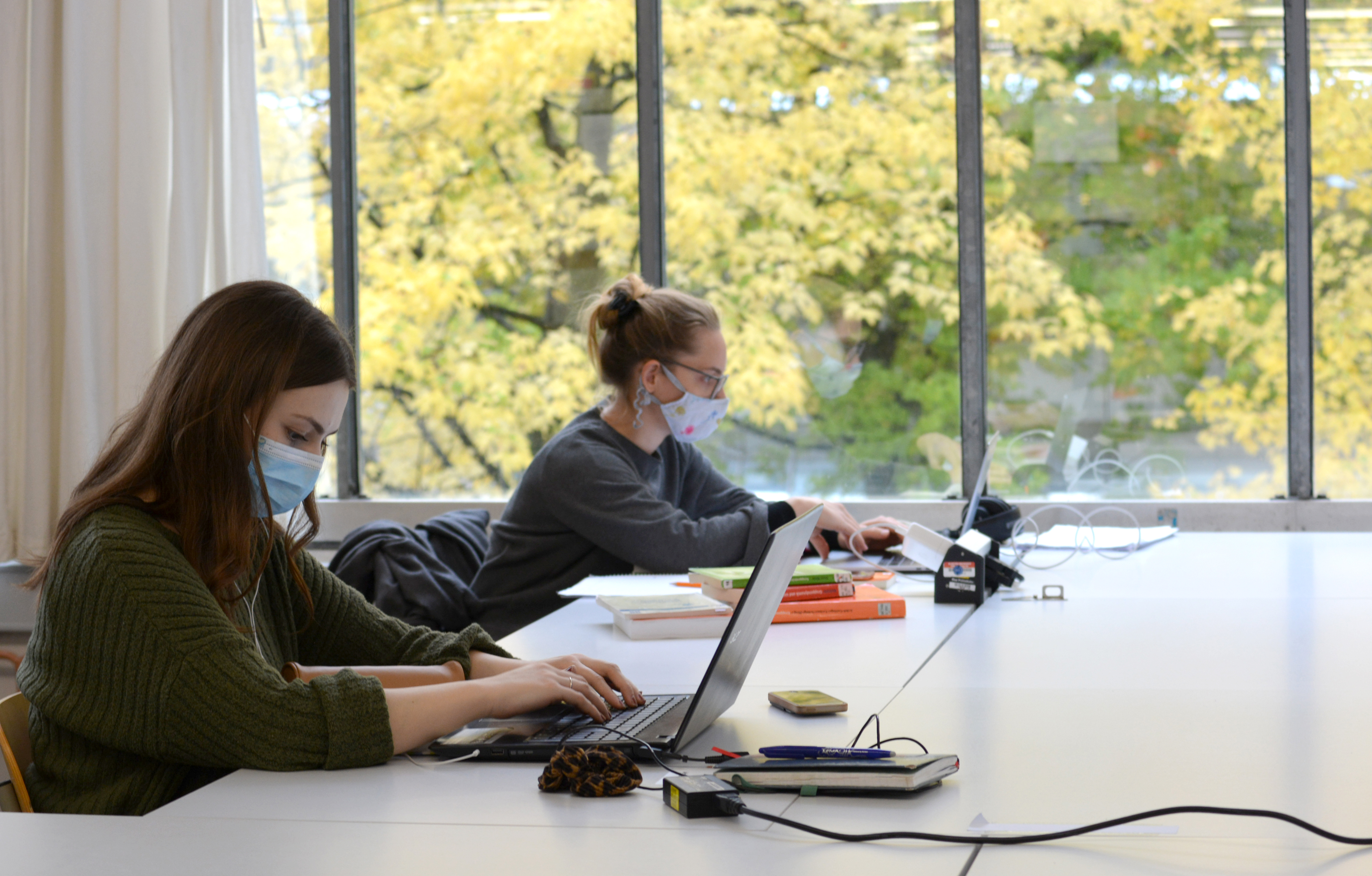 Zwei Personen mit Maske arbeiten am Laptop