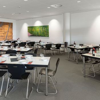 Set tables at the cafeteria, paintings on the wall in the background