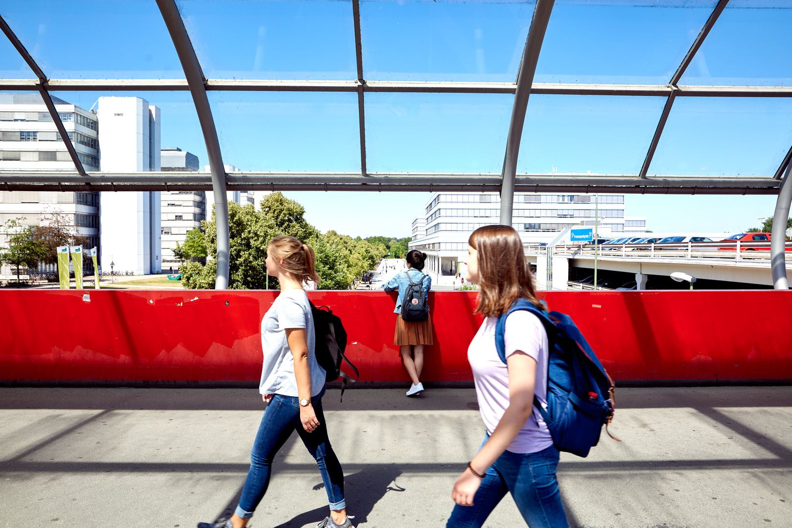 Drei Mädchen gehen über die Brücke zur Universität