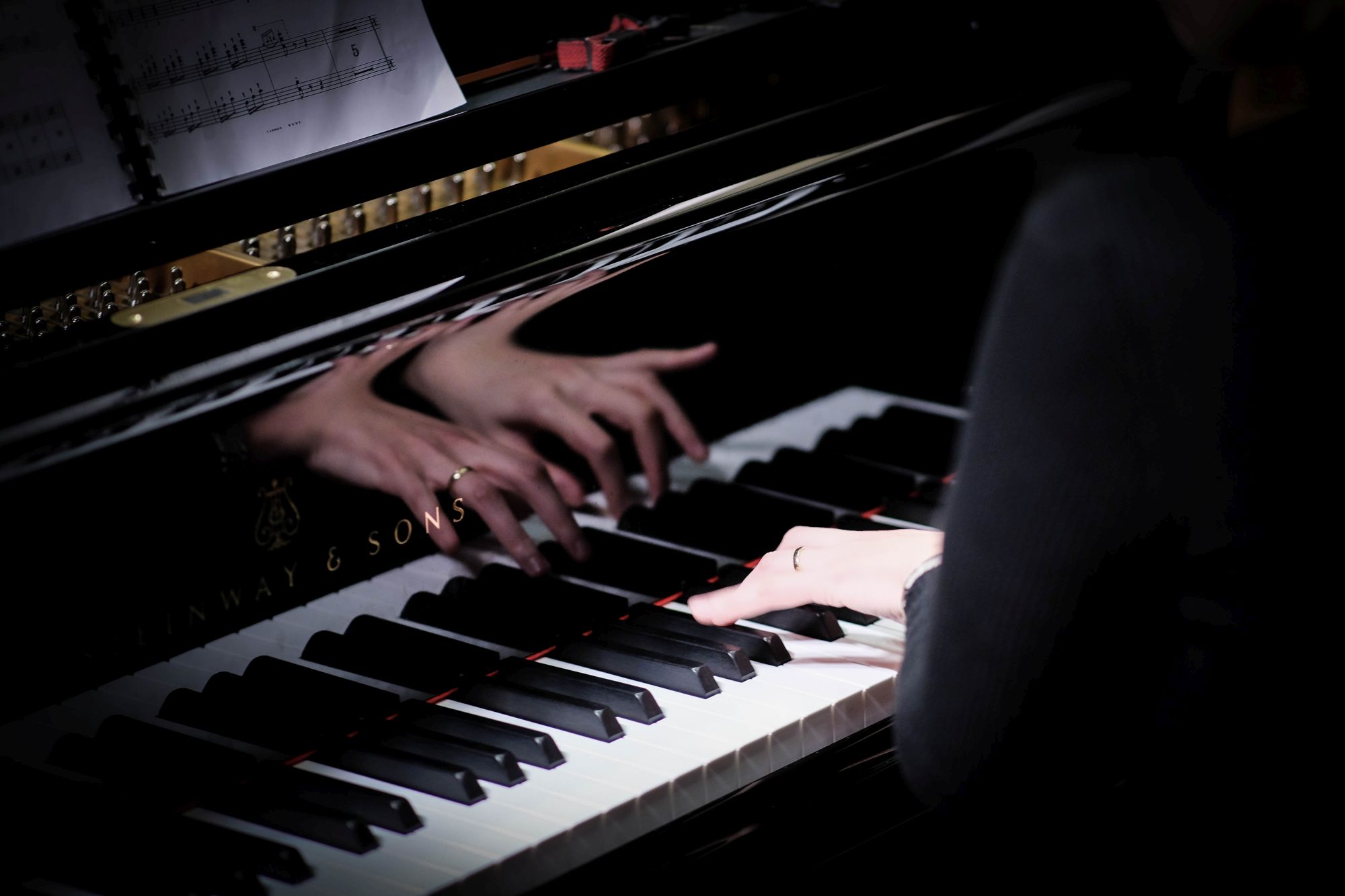 Hände einer Pianistin spielen auf dem Konzertflügel