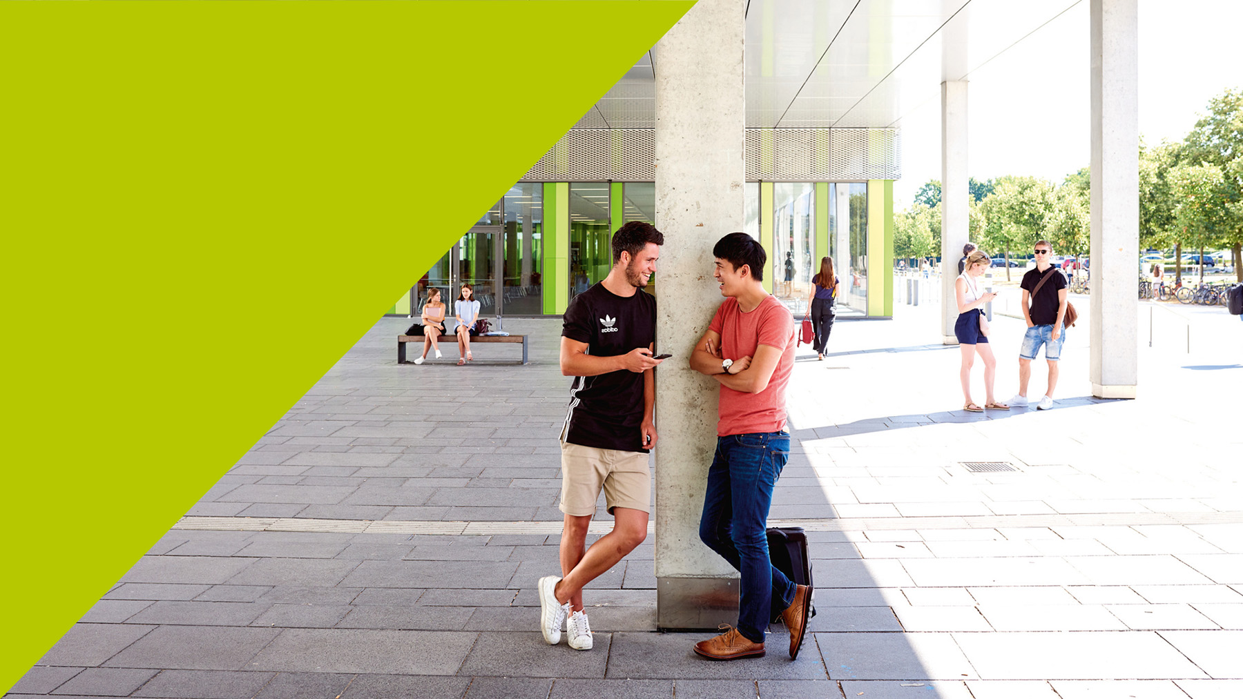 Studierende lehnen im Gespräch an einer Säule