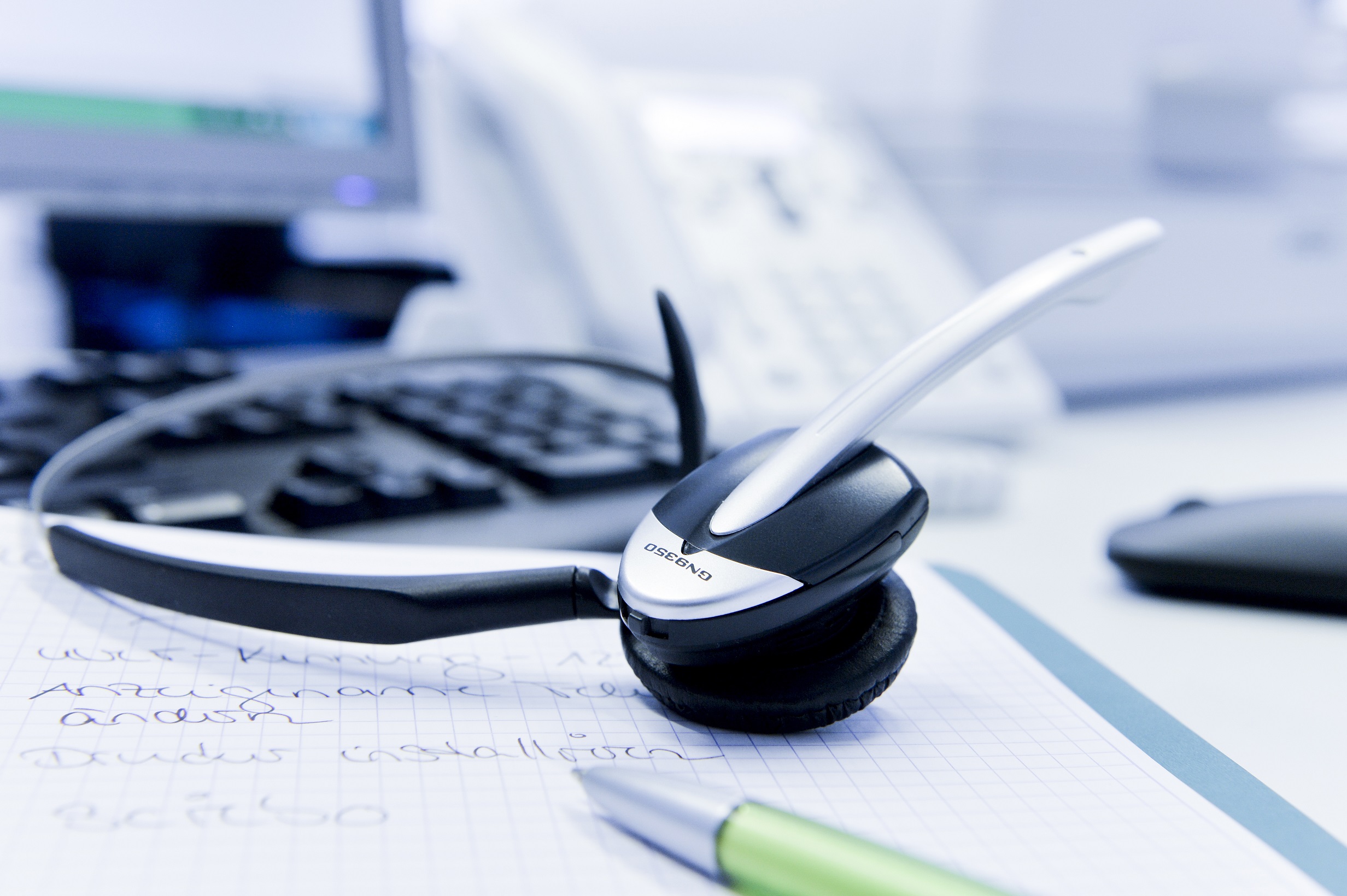 Schreibtisch mit Headset, Stift, Notizen, Tastatur und Maus