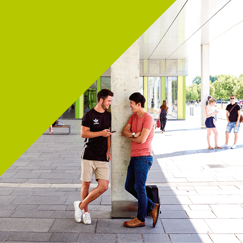 Studierende lehnen im Gespräch an einer Säule