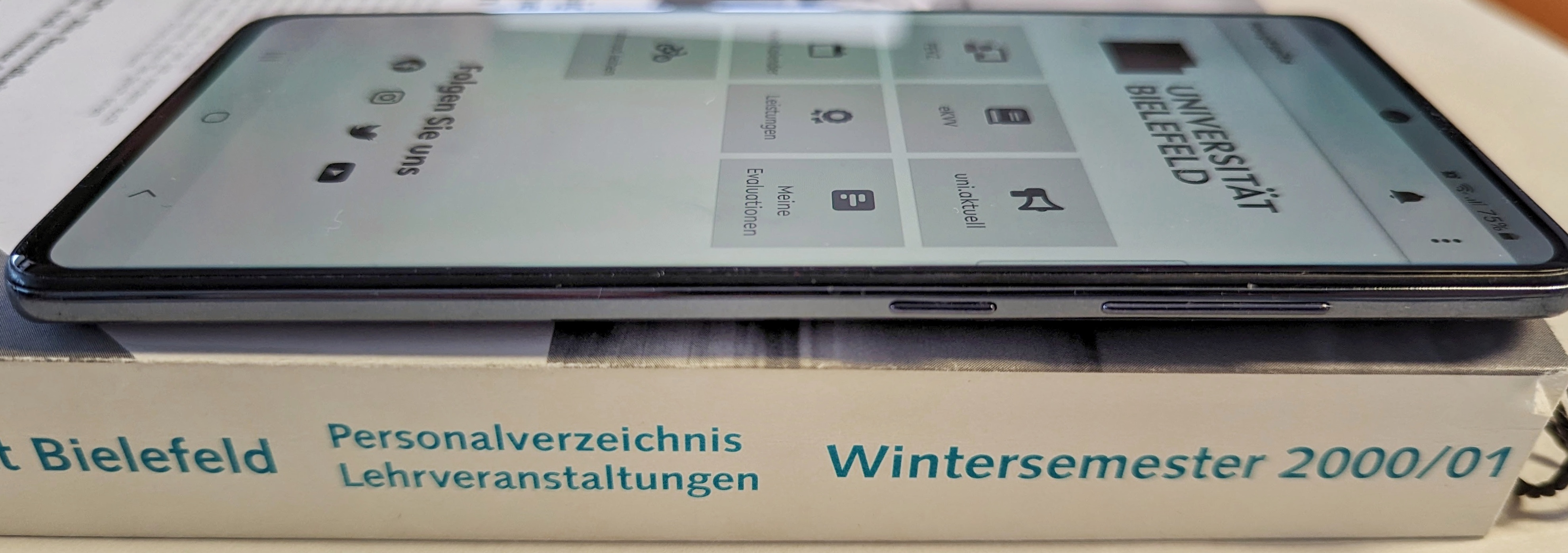 Handy mit geöffneter BIS-App liegt auf einem alten Vorlesungsverzeichnis