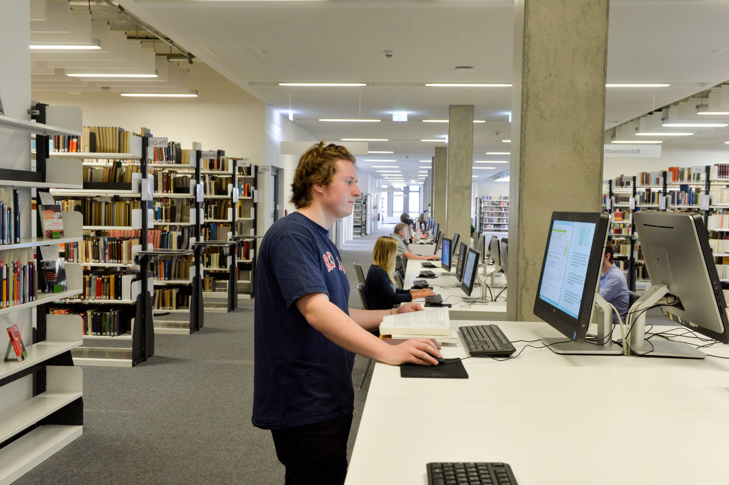 Foto einer Person am Laptop in der Bibliothek