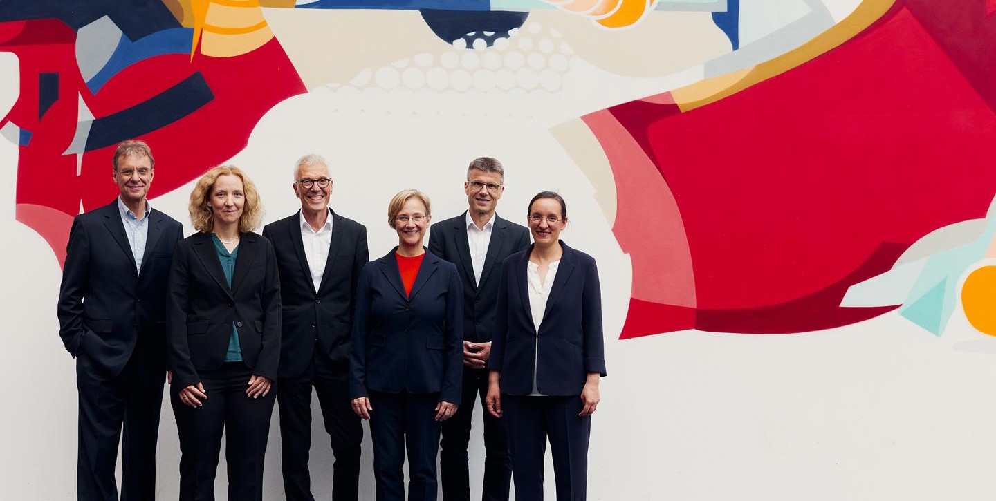 Die sechs Rekatoratsmitglieder der Universität Bielefeld stehen vor der Graffitiwand in der zentralen Universitätshalle.