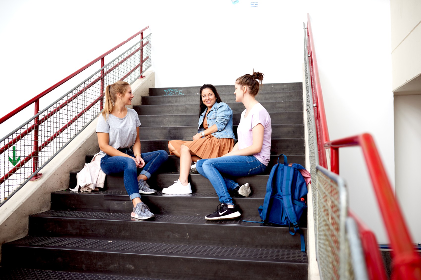 Studierende sitzen vor Wandgemlde in der Unihalle