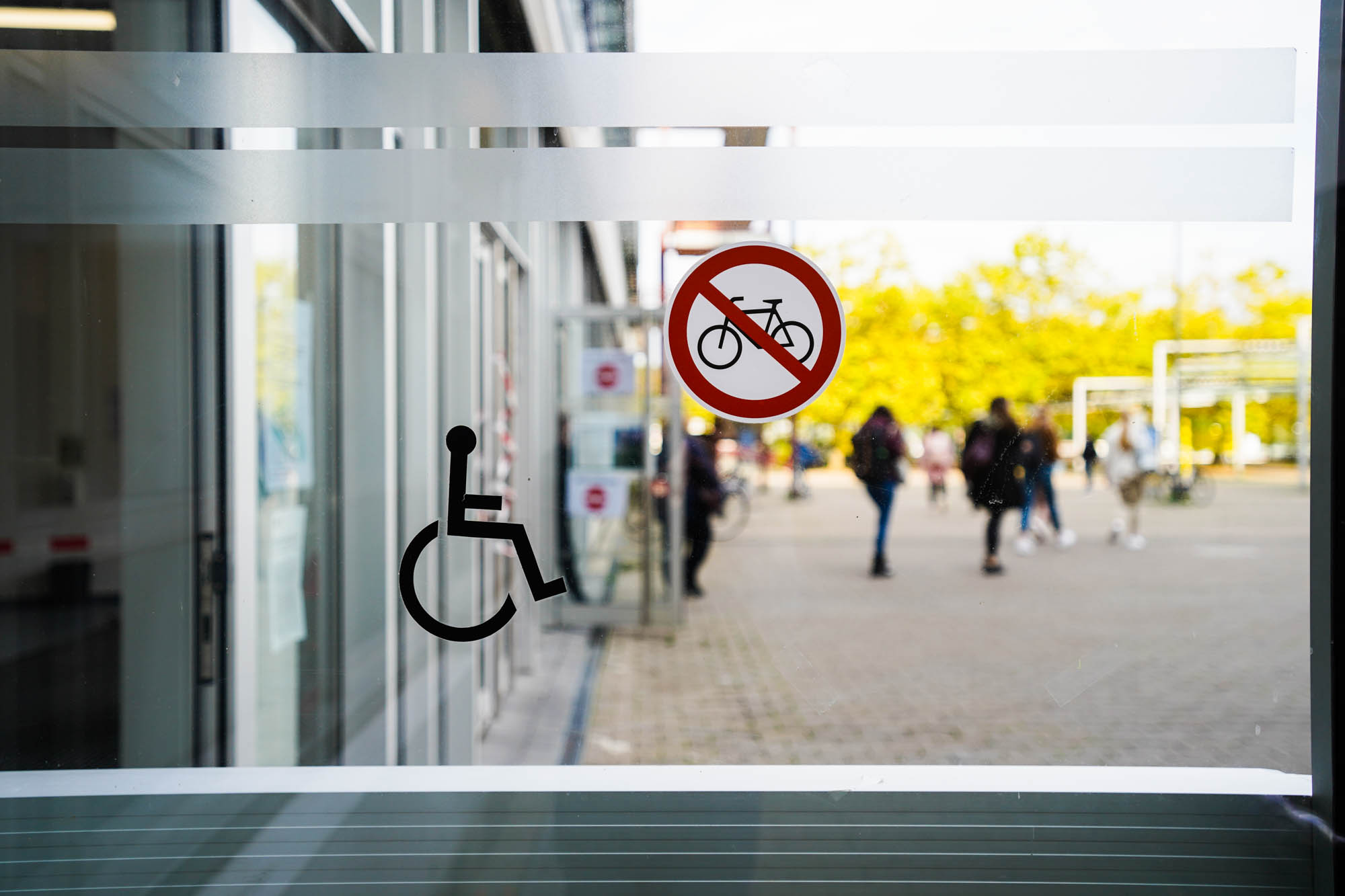Entrance door to Bielefeld University with a symbol of a wheelchair user and a bicycle prohibition sign