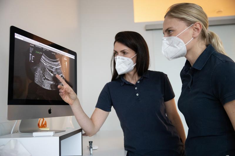 Zwei Ärztinnen sehen sich gemeinsam ein Ultraschallbild an.