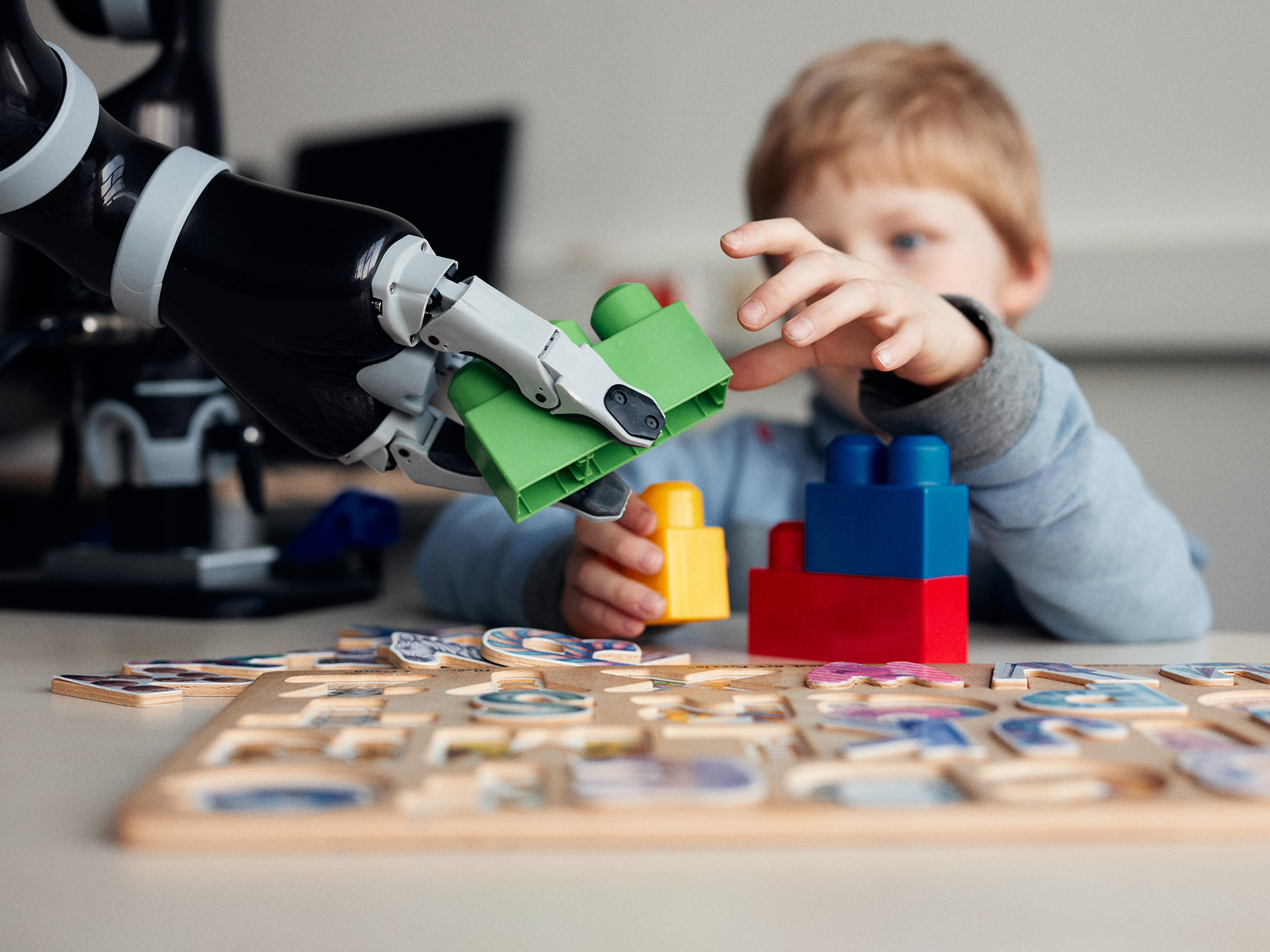 Ein Kind und ein Roboter spielen gemeinsam mit groen Steckbausteinen