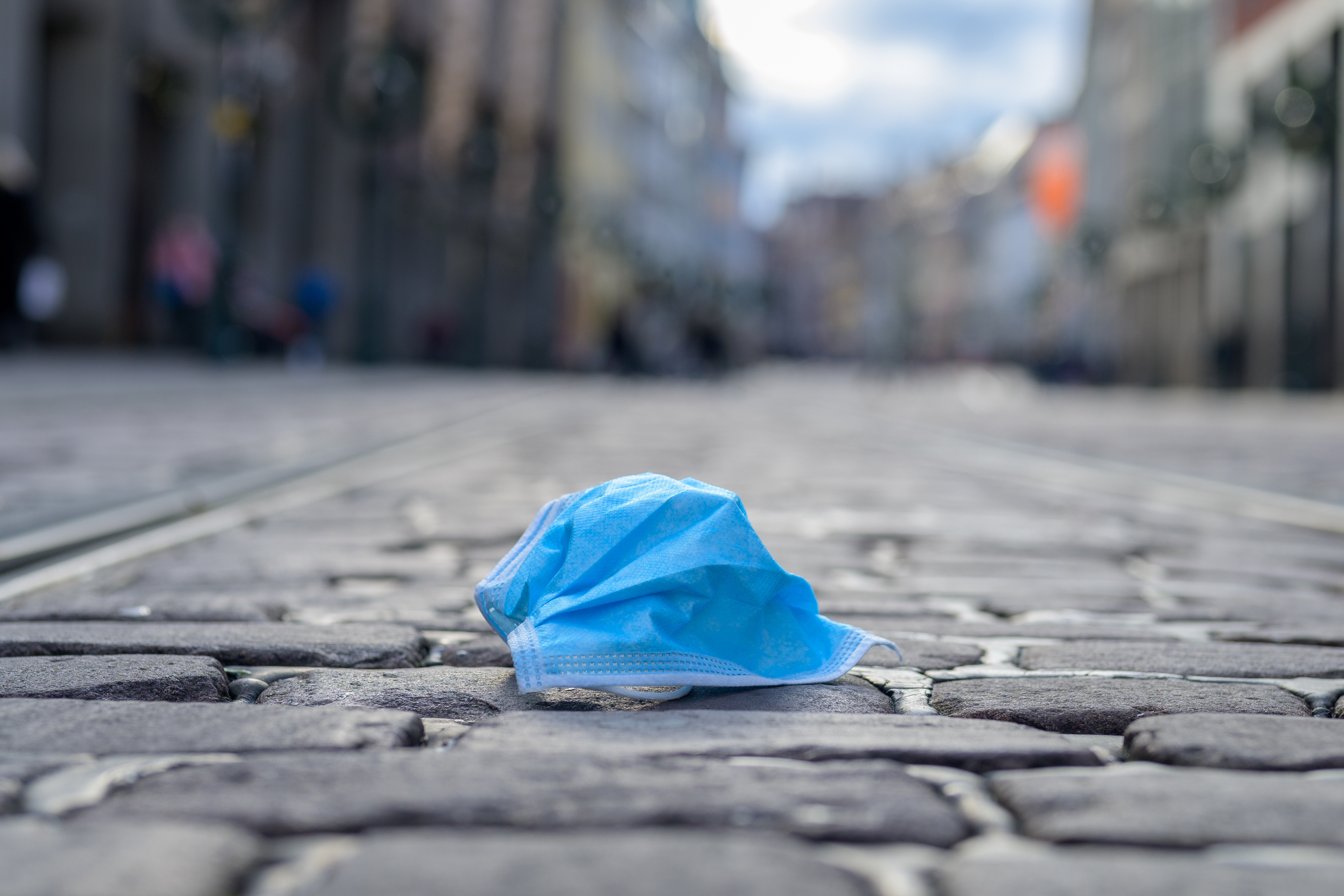 Discarded face mask lying in an urban street during the Covid-19 pandemic, in a low angle view with urban buildings