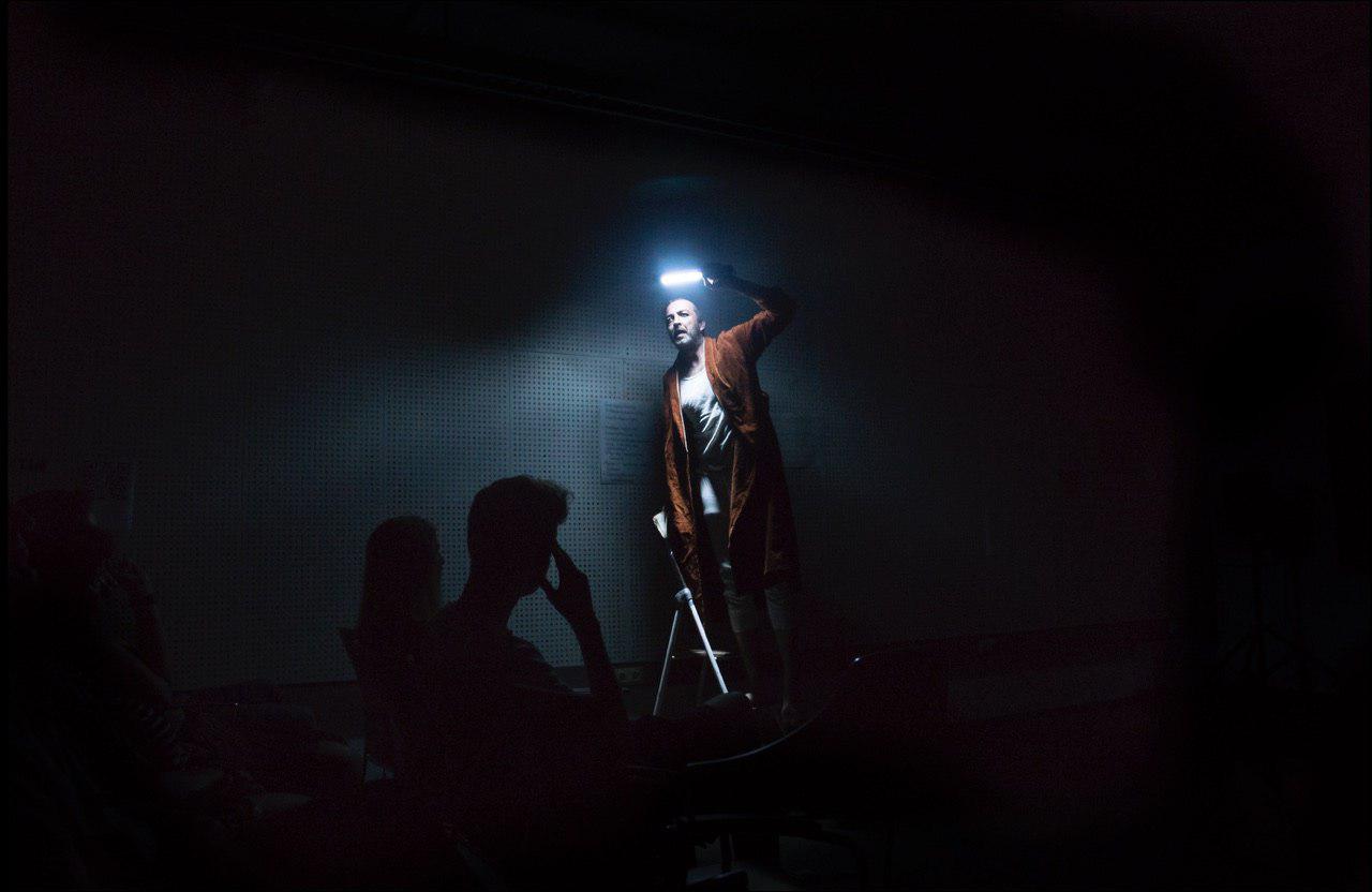 Ein Schauspieler leuchtet mit einer Lampe im dunklen Raum