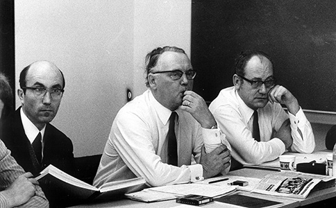 Niklas Luhmann, Helmut Schelsky und Dietrich Storbeck sitzen nebeneinander, vor ihnen zahlreiche Schriften